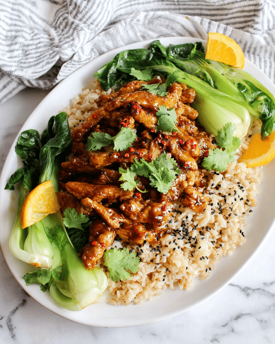 A white oval plate holds a dish with three main layers. The bottom layer is light brown cooked rice spread evenly across the plate. On top of the rice, there is a generous layer of glazed dark brown cooked meat pieces, with a shiny and sticky appearance, garnished with small bright green cilantro leaves. The sides of the plate are decorated with vibrant green bok choy vegetables, some with darker green leaves and lighter green stems. Small orange slices are placed around the dish adding a fresh contrast. The plate is set on a white marbled surface with some cilantro leaves scattered nearby. photo taken with an iphone --ar 4:5 --v 7