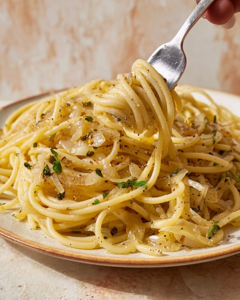 A close-up of a white plate filled with thick, golden-yellow spaghetti noodles mixed with sautéed translucent onions and small green herb leaves scattered throughout. The noodles have a slight shine from the light sauce coating them, and cracked black pepper is visible on top. A woman’s hand holds a shiny silver fork twirling a small portion of the noodles near the center of the plate. The plate sits on a white marbled surface with a light and warm tone in the background. photo taken with an iphone --ar 4:5 --v 7