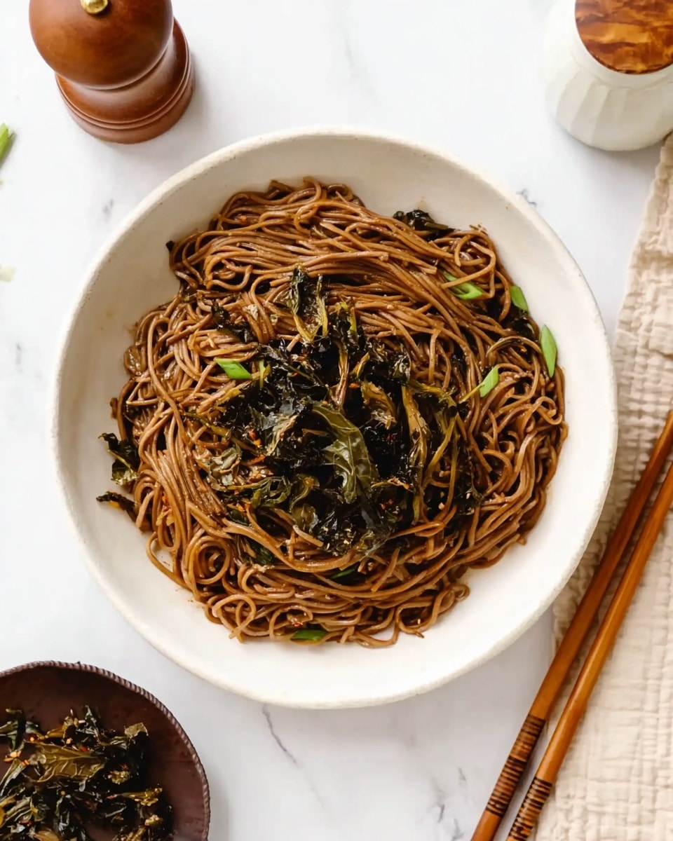 A white bowl filled with thin, dark brown noodles sitting on a white marbled surface. The noodles are layered densely, and on top, there is a small pile of crispy, dark green and brown leafy vegetables scattered in the center. Next to the bowl, there are brown wooden chopsticks on the right and a white jar with a wooden lid in the top right corner. A dark brown small dish with more crispy leaves is placed in the bottom left corner. In the top left, there is a wooden pepper grinder. Photo taken with an iphone --ar 4:5 --v 7