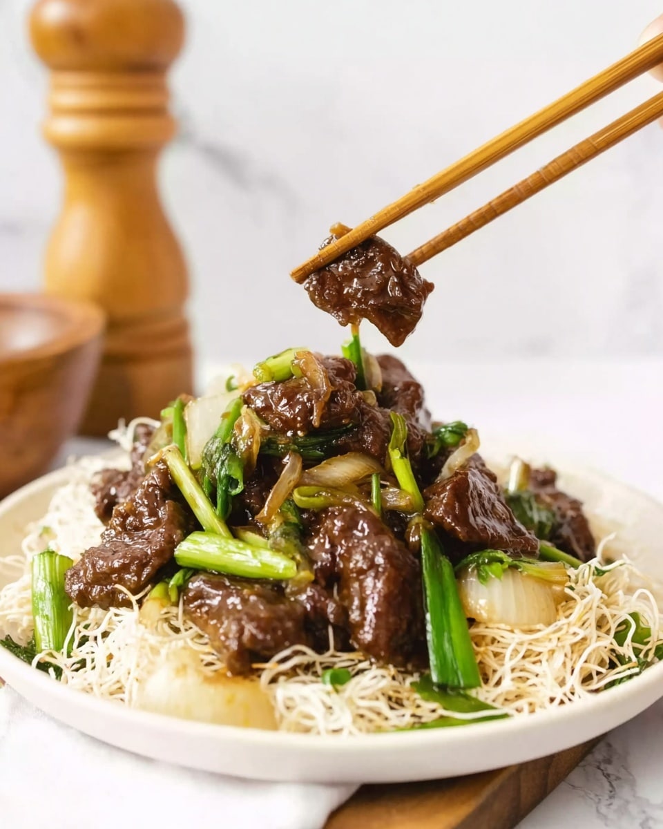 The image shows a white plate filled with several layers of food. The bottom layer is a bed of thin, white crispy noodles that look crunchy. On top of that, there are pieces of dark brown grilled meat, glistening with a shiny sauce. Green onions cut in long pieces are scattered among the meat, adding bright green color. Some white pieces of cooked onion are also mixed with the meat and green onions. A woman’s hand holding light brown chopsticks is picking up one piece of meat along with a green onion and onion slice. The background is a white marbled surface with a wooden pepper grinder and a wooden bowl blurred in the distance. photo taken with an iphone --ar 4:5 --v 7