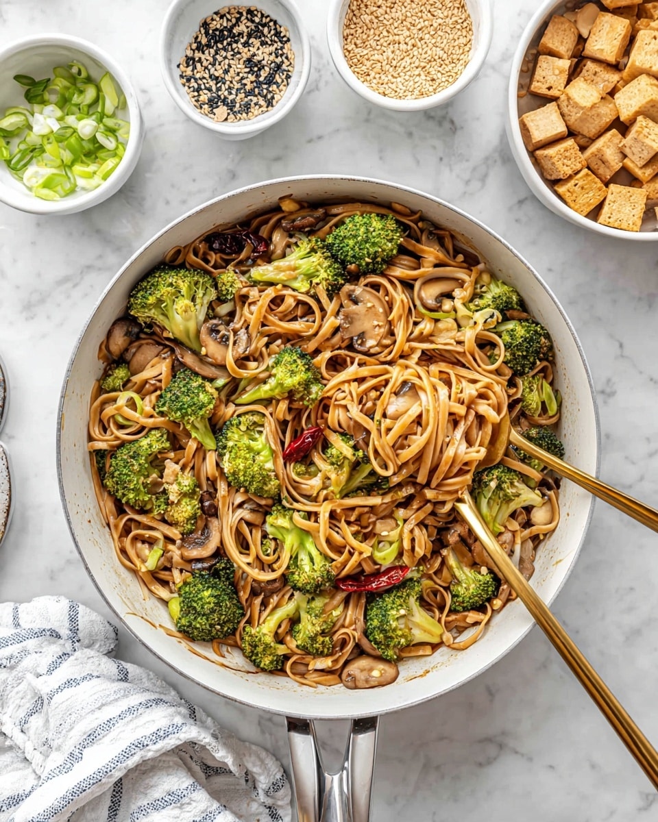 In a deep white pan, there is a mix of flat brown noodles, bright green broccoli florets, and light brown sliced mushrooms layered evenly throughout. Among the noodles and vegetables, there are a few whole dried red chili peppers scattered here and there. A golden fork and spoon are placed inside the pan, with the fork slightly lifting some noodles and broccoli, showing the mix's texture. Surrounding the pan are small white bowls containing black and white sesame seeds, chopped green onions, cubed tofu with a brown sauce drizzle, and crushed peanuts. The whole scene is set on a white marbled surface with a white cloth featuring thin blue stripes partially visible at the bottom left photo taken with an iphone --ar 4:5 --v 7