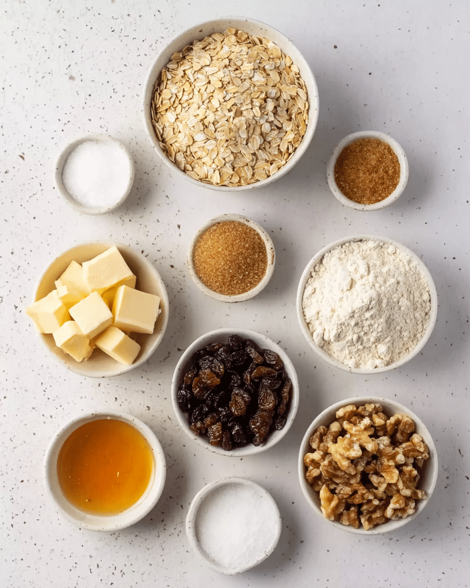 The image shows eight small white bowls arranged on a white marbled surface. At the top center is a bowl filled with light brown rolled oats. To the left, a bowl contains pale yellow cubes of butter. Below the oats, a bowl holds light brown sugar with a soft texture. To the right of the sugar, a bowl is filled with white flour, showing a fine powder texture. Below the flour is a bowl filled with dark brown raisins, shiny and slightly wrinkled. At the bottom center, a bowl contains chopped walnuts, light brown with uneven pieces. To the left of the walnuts, a small bowl has golden honey with a thick texture. Above the honey, a small bowl contains white granulated sugar. The overall view is neat, with each ingredient clearly visible. Photo taken with an iphone --ar 4:5 --v 7