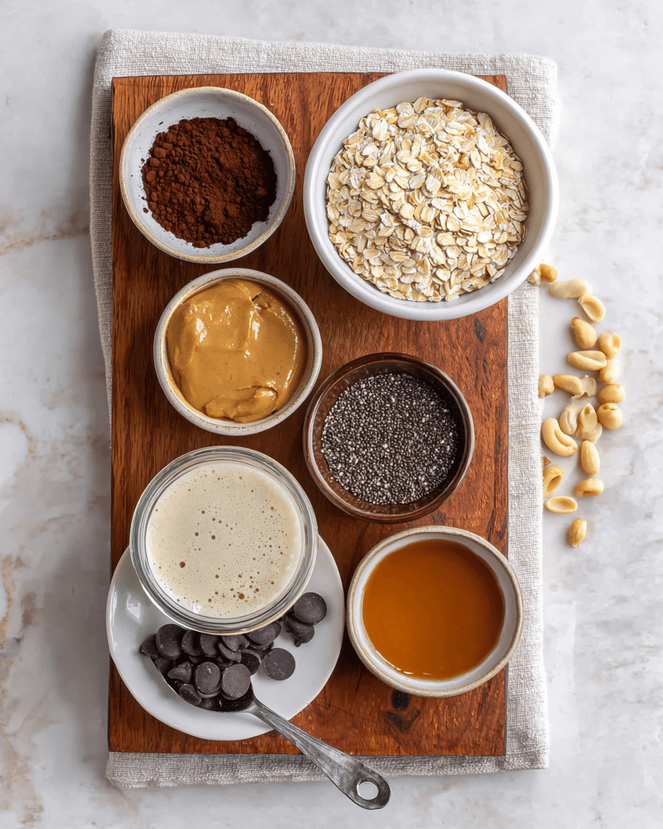 The image shows six small bowls and dishes arranged on a wooden board with a light cloth underneath, placed on a white marbled surface. At the top right, there is a white bowl full of pale yellow rolled oats. Below it to the right, a small brown bowl contains tiny dark brown chia seeds. Next to it on the left, a small white bowl is filled with rich brown cocoa powder. Below these, there is a clear glass jar filled with cream-colored liquid with a few bubbles. To the left, a small beige bowl holds smooth light brown peanut butter. Above it, a white bowl with dark edges contains golden brown maple syrup. At the bottom left, a small white plate holds dark glossy chocolate chips with a silver measuring spoon resting on the plate. Scattered peanuts are seen on the wooden board and around it. photo taken with an iphone --ar 4:5 --v 7