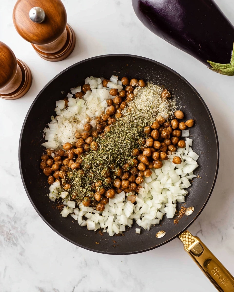 A black frying pan with a golden handle sits on a white marbled surface, filled with three main layers: the bottom layer consists of evenly chopped white onions, the middle layer is made up of small, brown cooked chickpeas scattered across the onions, and the top layer shows clusters of various green dried herbs sprinkled mostly over the chickpeas. To the top left of the pan, two wooden pepper and salt grinders lie on the white marbled surface, and to the top right, there is a whole dark purple eggplant. photo taken with an iphone --ar 4:5 --v 7