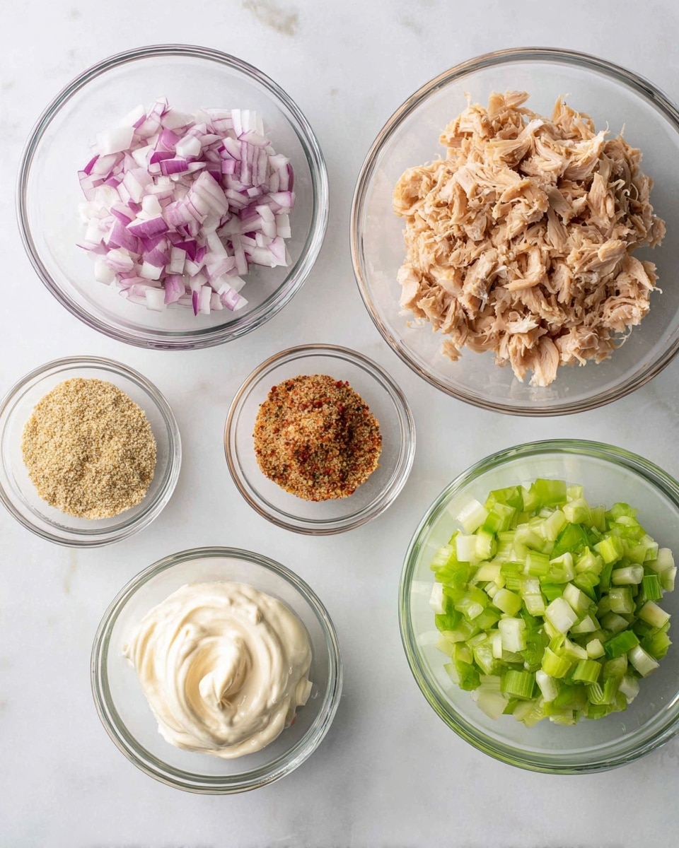 Six clear glass bowls sit on a white marbled surface, each with a different ingredient. The top right bowl is filled with a light brown, shredded and chopped cooked chicken. To its left, a bowl holds finely chopped red onions in shades of purple and white. Below the onion bowl, slightly left, is a small bowl of grainy light brown mustard. To the left of the mustard bowl, another small bowl contains a mixture of light brown and red seasoning. Above the seasoning bowl, a bowl is filled with swirled white mayonnaise. At the bottom right, a bowl is filled with chopped celery showing bright green colors and varying textures. All bowls are arranged neatly and evenly spaced. photo taken with an iphone --ar 4:5 --v 7