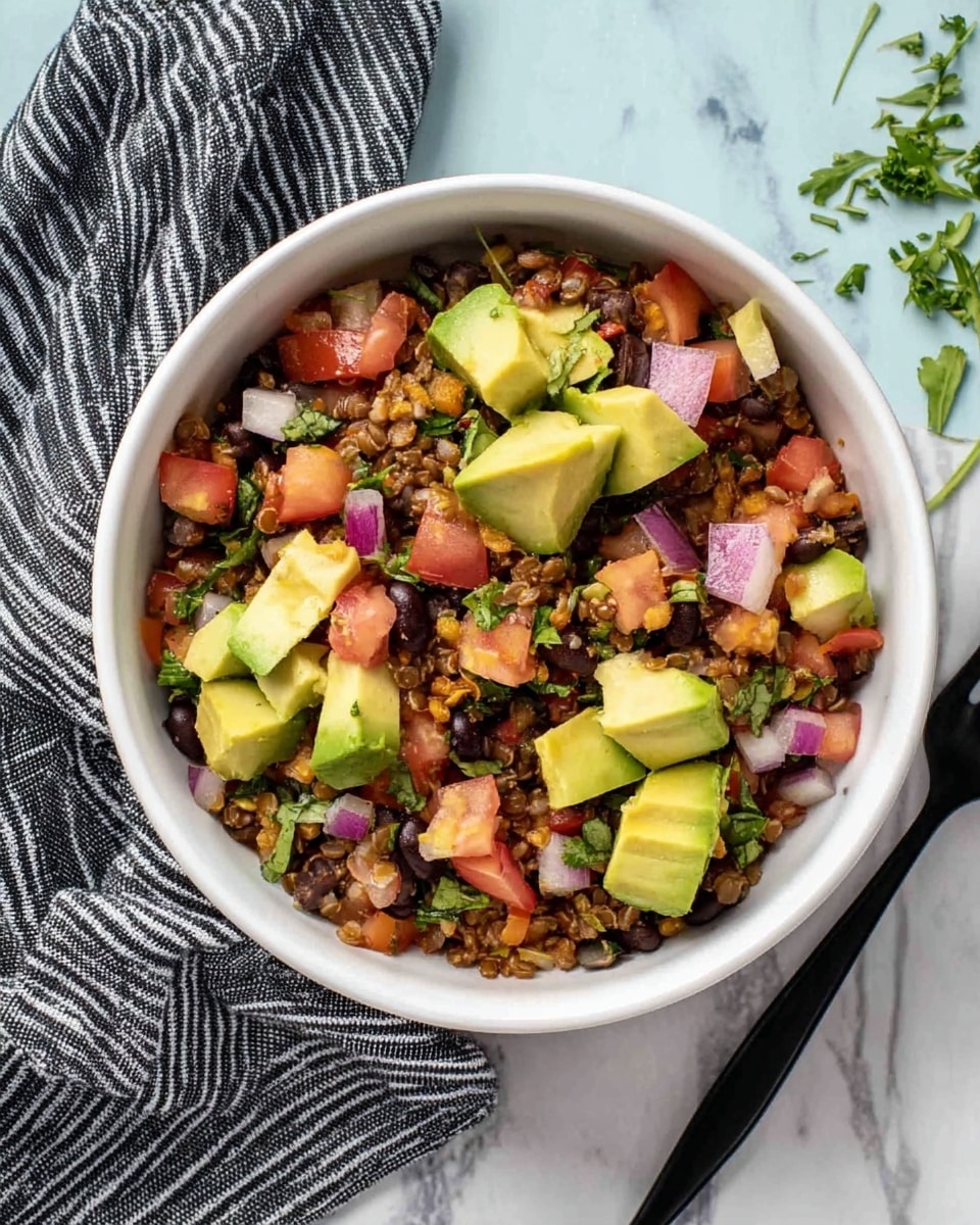 A white bowl filled with a colorful mix of diced avocado, chopped tomatoes, black beans, small pieces of red onion, and finely chopped greens, all mixed with a base of brown grains or lentils. The avocado pieces are bright green and evenly distributed on top. The bowl is placed on a white marbled surface with a folded black and white striped cloth on the left side and a few green herb sprigs on the right near a black fork. The image is bright and clear, showing the fresh, natural textures of the ingredients. photo taken with an iphone --ar 4:5 --v 7