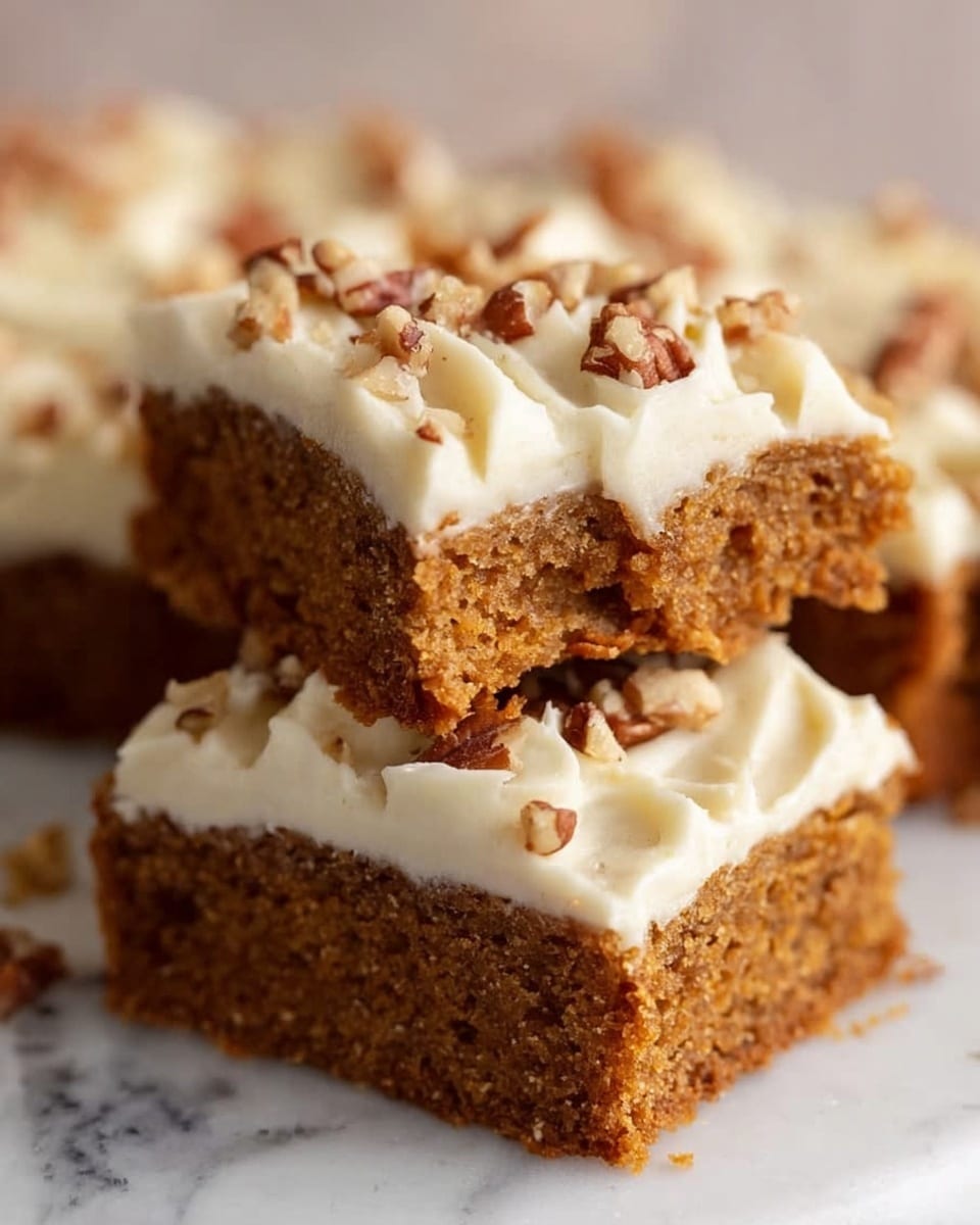 The image shows two square pieces of a brown cake stacked on a white marbled surface. The bottom layer is a dense textured cake with a soft crumb. The top layer is a thick swirl of white creamy frosting decorated with small pieces of chopped nuts sprinkled on top. The back piece has a bite taken out of it, revealing the inside of the cake and frosting. The photo taken with an iphone --ar 4:5 --v 7
