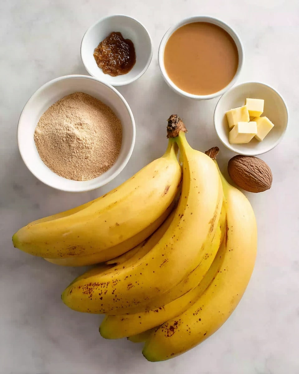 A group of four ripe yellow bananas with some brown spots sits on a white marbled surface near five small white bowls. One bowl holds a light tan powder, another contains small yellow butter pieces, a third has dark brown sugar, a fourth is filled with a smooth light brown liquid, and the smallest bowl holds two whole nutmegs. photo taken with an iphone --ar 4:5 --v 7
