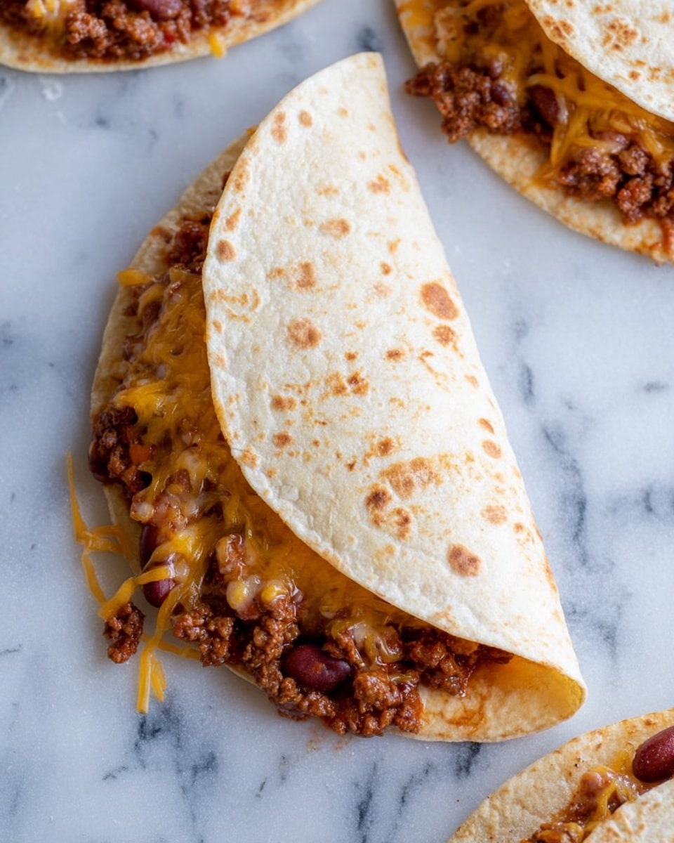 A close-up image shows a soft, folded taco on a white marbled surface, revealing two main layers inside: the bottom layer is a mix of browned ground meat and beans with a rich reddish-brown color, topped with a layer of melted yellow and white cheese that is warm and stringy, some cheese and meat slightly spilling out at the edges. The taco shell is light beige with small toasted spots giving a rustic texture. Around the main taco, parts of other folded tacos are visible at the edges of the frame on the same white marbled surface. Photo taken with an iphone --ar 4:5 --v 7