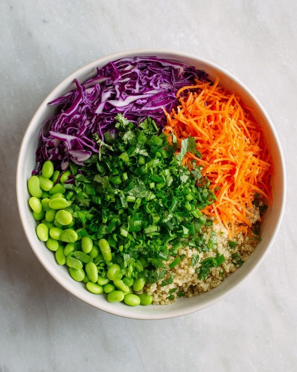 A white bowl filled with six different layers of fresh vegetables and grains arranged side by side. Starting from the left, there is shredded purple cabbage with a slightly shiny texture, next to bright orange grated carrots. Beside the carrots, there is a pile of finely chopped fresh green mint leaves, followed by light green edamame beans. Next to the beans, there are small grains of light beige quinoa partially visible. On top of the quinoa and beans, there is a layer of chopped green onions mixed with chopped cilantro covering part of the bowl. The bowl is placed on a white marbled surface. Photo taken with an iphone --ar 4:5 --v 7
