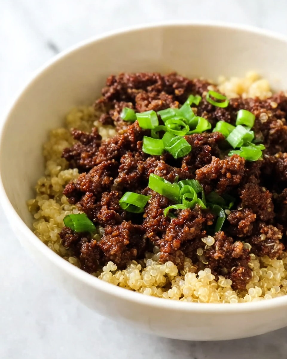 The image shows a white bowl with two main layers: the bottom layer is light-colored cooked quinoa with a soft, grainy texture, while the top layer consists of dark brown cooked ground meat with a crumbly texture. The meat is scattered unevenly over the quinoa. Small pieces of bright green chopped scallions are sprinkled on top of the meat, adding a fresh, colorful contrast. The bowl is placed on a white marbled surface. photo taken with an iphone --ar 4:5 --v 7