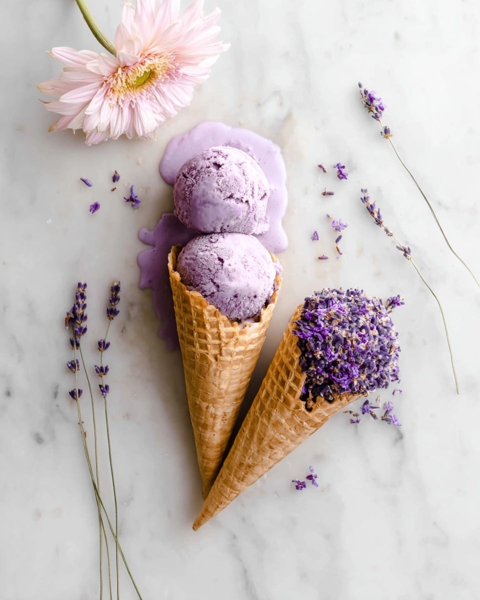 The image shows two waffle cones on a white marbled surface; the first cone is upright filled with three scoops of light purple ice cream that has a slightly rough texture and is beginning to melt, with some melting ice cream forming droplets around the cone base. The second cone lies on its side and is filled with small purple flowers that have dense petals and a soft look. Surrounding the cones are a single light pink flower with a yellow center at the top left and a few thin sprigs of lavender with tiny purple buds on the right side, adding a natural and delicate touch. photo taken with an iphone --ar 4:5 --v 7