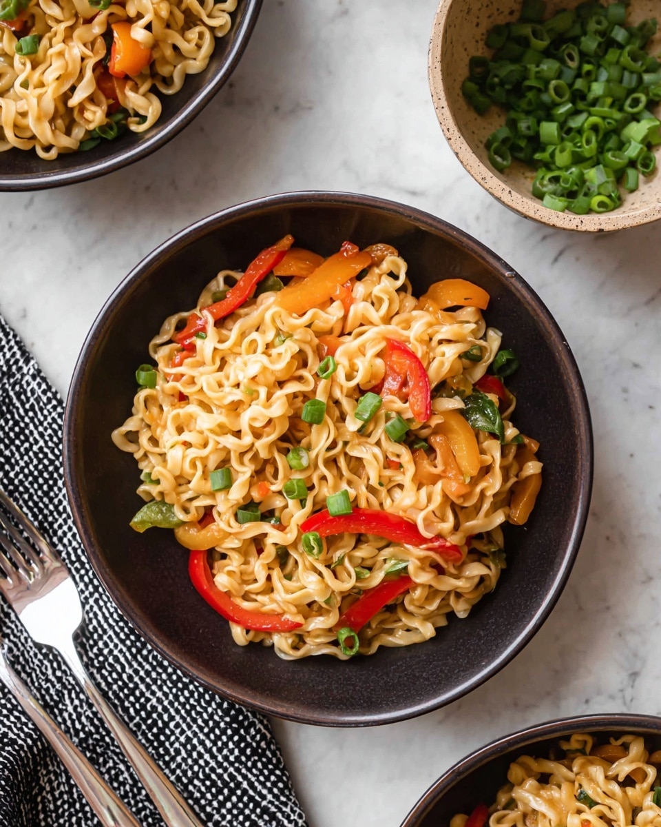 A close-up image shows a dark bowl filled with cooked curly noodles that are pale yellow, mixed with orange and red bell pepper strips layered throughout, and sprinkled with chopped green onions on top. The noodles have a light shine and soft texture. Next to the bowl, on the white marbled surface, there is a tan bowl filled with more chopped green onions. The scene includes a black and white checkered cloth and two forks placed nearby. Partial views of similar dark bowls with the same noodle dish appear at the top right and bottom right edges of the image. Photo taken with an iphone --ar 4:5 --v 7