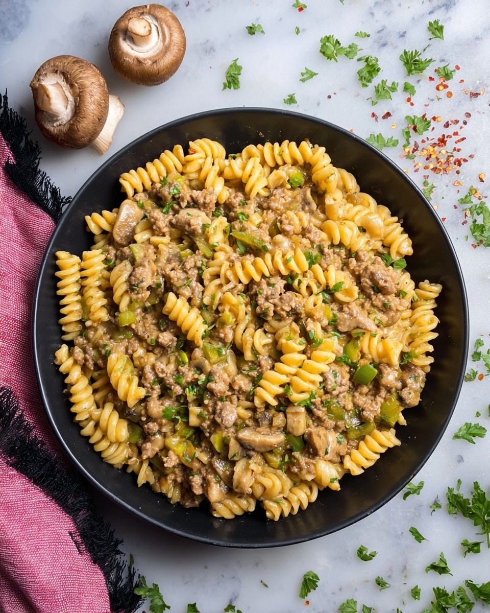 A black bowl filled with a creamy pasta dish made of three parts: yellow spiral pasta, light brown ground meat mixed with small chunks of brown mushrooms, and bright green bell pepper pieces all evenly mixed together. Small bits of fresh green parsley are sprinkled on top, adding color and texture. The bowl sits on a white marbled surface, with two whole brown mushrooms nearby and some scattered parsley leaves and red pepper flakes around. A folded pink cloth with black edges is placed beside the bowl. Photo taken with an iphone --ar 4:5 --v 7