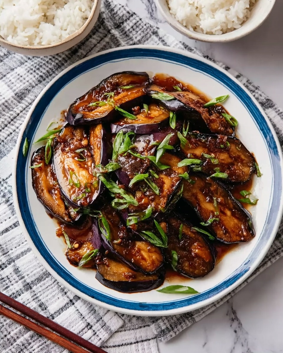 A white round plate with a blue rim holds a dish of dark brown eggplant slices cooked in a shiny sauce, arranged in a slightly overlapping pattern. Small pieces of bright green chopped scallions are sprinkled on top, adding a fresh contrast to the rich, glossy texture of the eggplant. The plate sits on a white and grey checkered cloth over a white marbled surface, with two white bowls of steamed white rice and a pair of brown wooden chopsticks placed near the top edge of the image. Photo taken with an iphone --ar 4:5 --v 7
