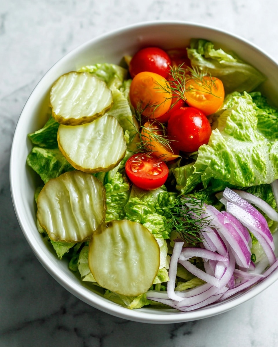 A white bowl filled with fresh green lettuce leaves at the bottom, creating a textured leafy layer. On the left side, there are five crinkle-cut pickle slices with a light green color and translucent centers, resting on the lettuce. On the top right, bright red and orange cherry tomato halves are scattered, garnished with small sprigs of dill. At the bottom right, thinly sliced rings of purple onion add a contrasting color and delicate texture. The bowl is placed on a white marbled surface. photo taken with an iphone --ar 4:5 --v 7