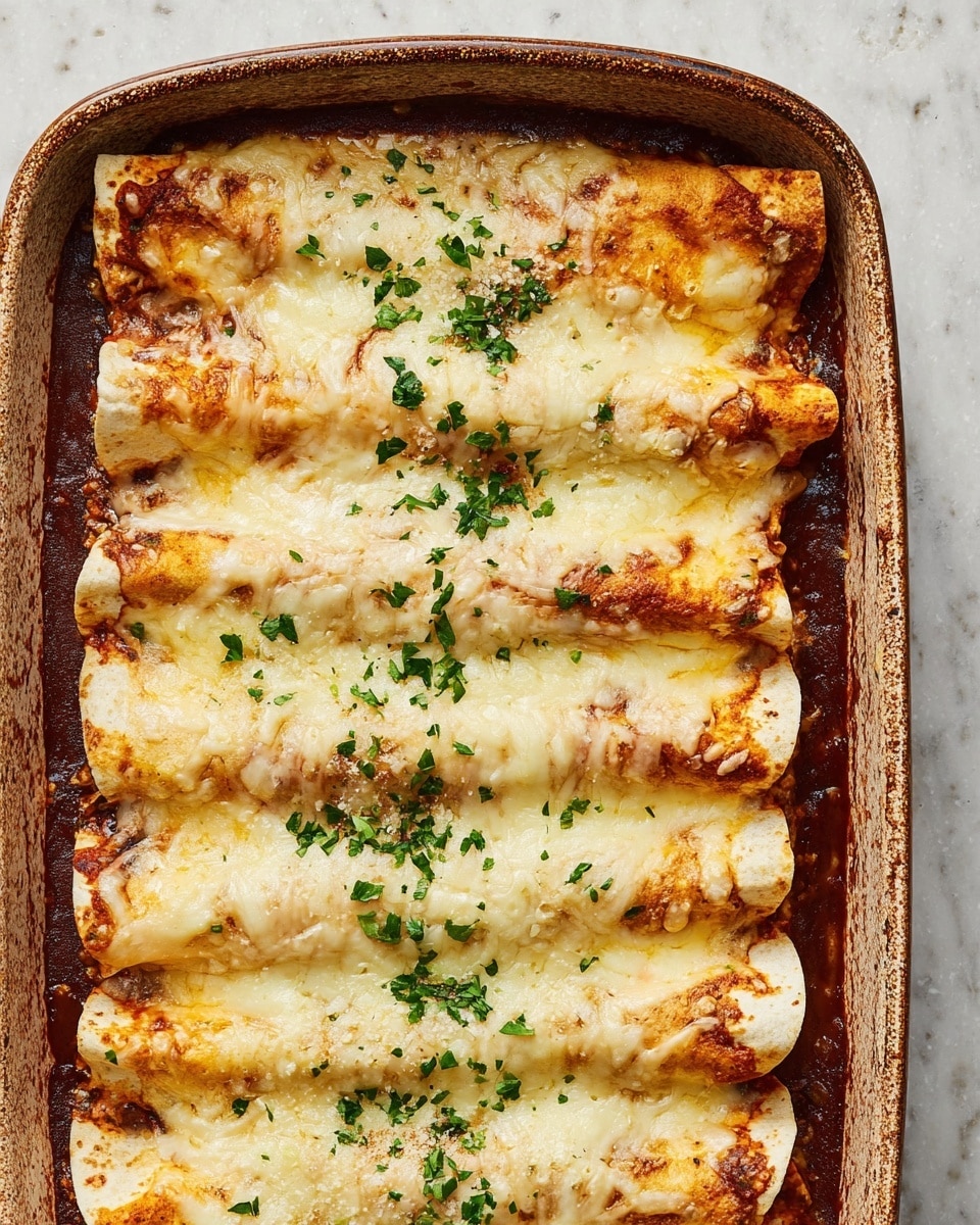 A close-up view of a baking dish filled with six rolled enchiladas placed side by side, each covered with a melted layer of creamy white cheese with slightly browned spots. Beneath the cheese, the soft tortillas show a golden-brown tint with some red sauce peeking through the edges and pooling slightly at the bottom corners. The dish is topped with small pieces of chopped green herbs scattered evenly across the surface. The baking dish itself is rectangular with slightly worn edges, sitting on a white marbled textured surface. photo taken with an iphone --ar 4:5 --v 7