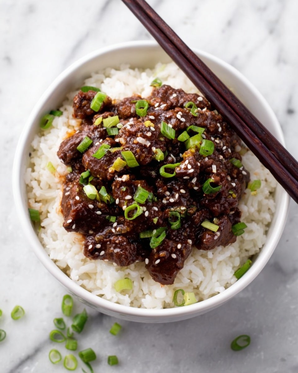 A white bowl filled with a base layer of fluffy white rice, topped with a thick layer of dark brown cooked beef pieces covered in sauce. The beef is garnished with chopped green onions and scattered white sesame seeds. A pair of dark brown chopsticks rests on the right edge of the bowl. The bowl is set on a white marbled surface with a few small pieces of green onion scattered around. Photo taken with an iphone --ar 4:5 --v 7