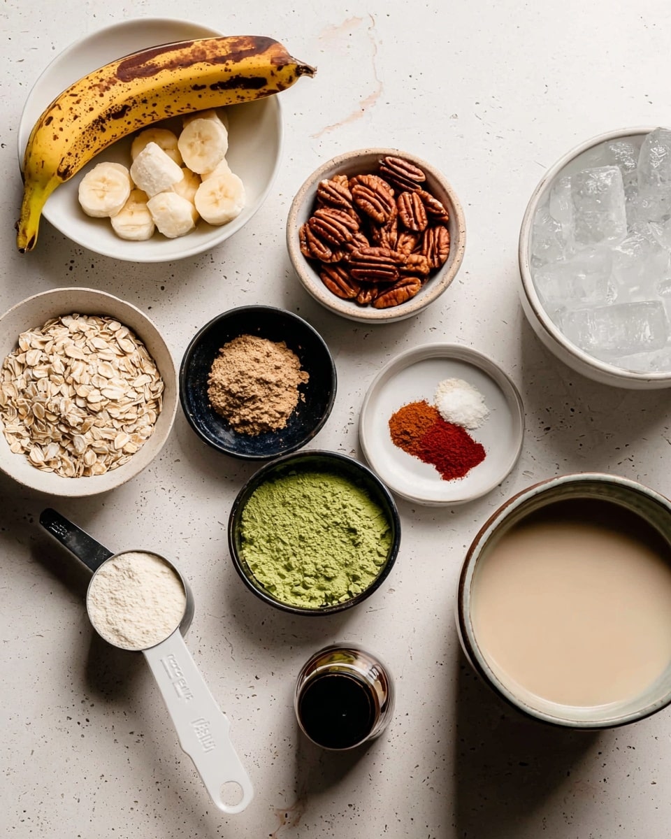 The image shows several small white bowls and measuring cups arranged on a white marbled surface. One bowl holds peeled bananas with one whole banana on top, another bowl contains pecans, and a small black bowl holds bright green powder. A white bowl contains rolled oats, and another small black bowl has two spices, one red and one white, side by side. There is a metal measuring cup full of a white creamy substance, a white plastic scoop holding light brown powder, and a small dark bottle with a black rim. On the right side, there is a white bowl with a dark rim filled with ice, and next to it, a white cup filled with beige liquid. The photo taken with an iphone --ar 4:5 --v 7