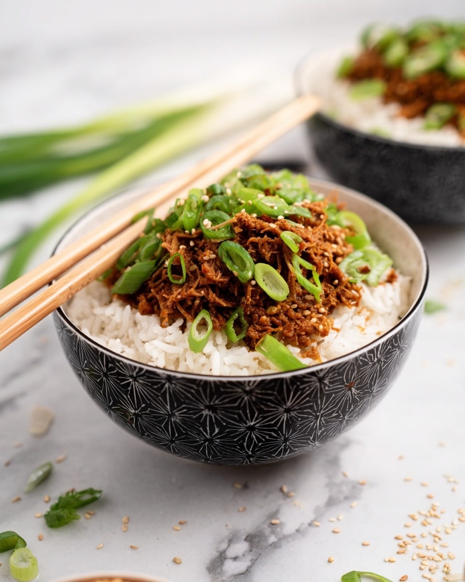 A white bowl with a black pattern is filled with a base layer of fluffy white rice, topped with a thick layer of shredded brown meat. On top of the meat, there are fresh bright green sliced scallions scattered evenly. A pair of light brown wooden chopsticks rests diagonally on the rim of the bowl. The bowl is placed on a white marbled surface, with some green scallion pieces and sesame seeds scattered around. Another similar bowl, slightly out of focus, is in the background. photo taken with an iphone --ar 4:5 --v 7