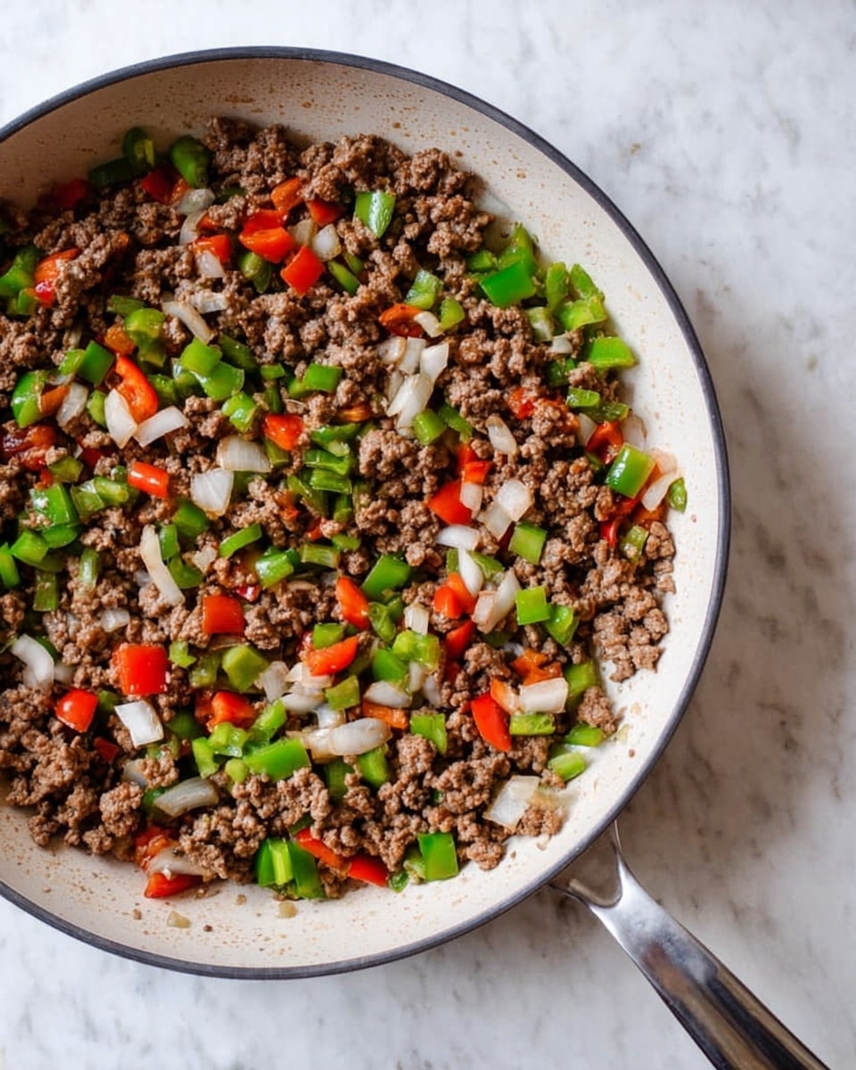A white pan filled with cooked ground beef mixed with evenly chopped green and red bell peppers and white onion pieces. The beef is crumbly and brown, while the bell peppers and onions add bright green, red, and translucent white colors that contrast with the meat. The pan handle extends to the right, resting on a white marbled surface. The mix looks freshly cooked with a slightly glossy texture, showing a well-blended combination of ingredients. photo taken with an iphone --ar 4:5 --v 7