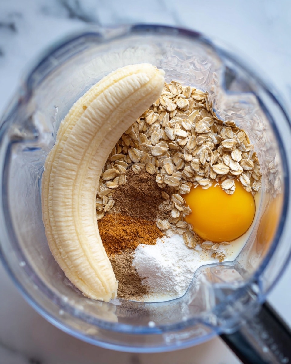Inside a clear blender container, there is a layered mix starting with a curved whole peeled banana lying on one side, a single bright yellow-orange egg yolk positioned near the center, and a generous pile of light tan rolled oats to the right and around the yolk. Below and around these ingredients, there is a small pool of white liquid, likely milk, and on top of the oats and close to the yolk, several small piles of brown cinnamon and white powder, possibly baking soda or baking powder. The blender is on top of a white marbled surface. photo taken with an iphone --ar 4:5 --v 7