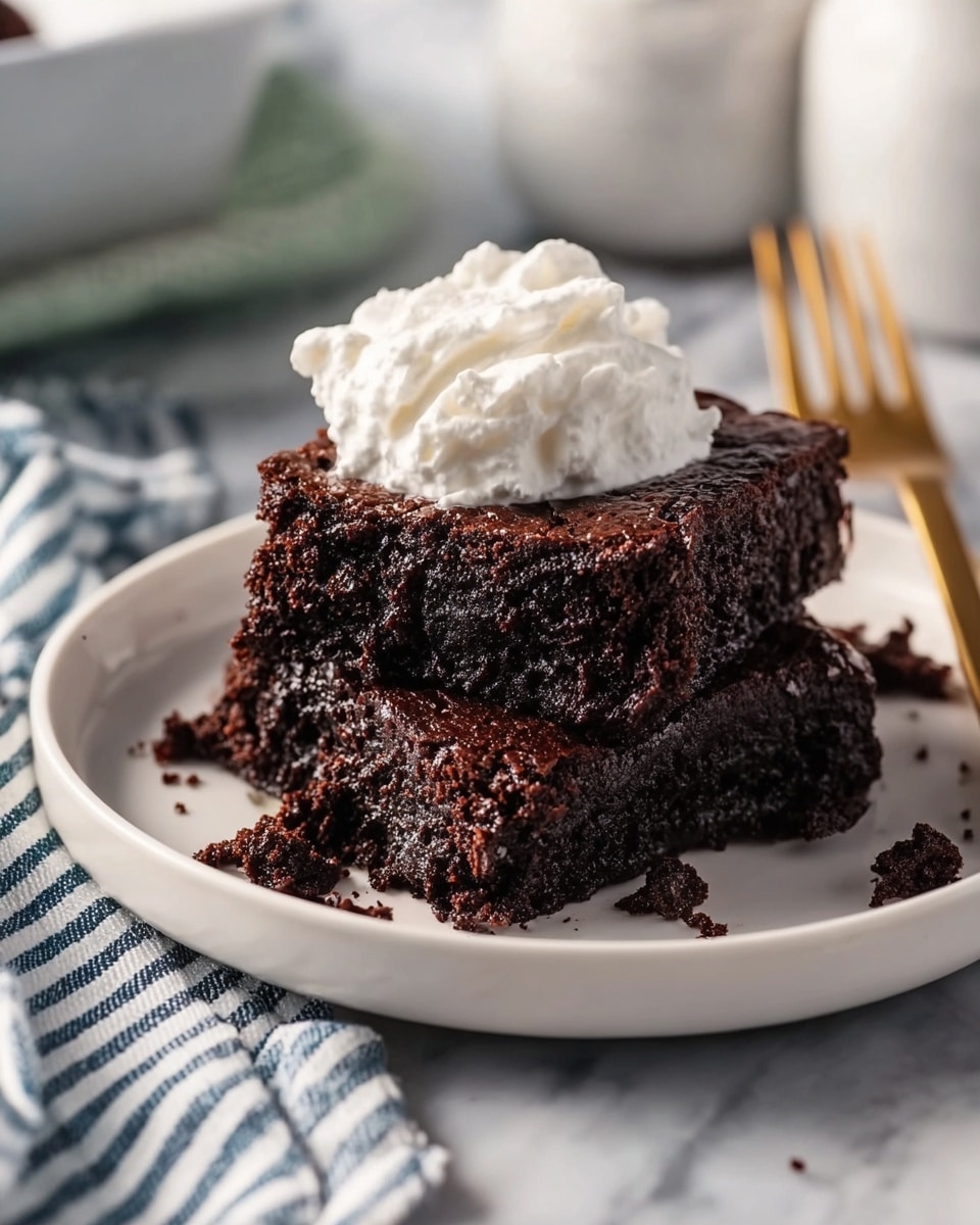 A white round plate holds two thick, dark brown chocolate brownies stacked slightly on top of each other, with a few crumbs scattered around. On top of the brownies is a dollop of white whipped cream, soft and fluffy with swirled peaks. The plate sits on a white marbled surface with a gold fork in the background and a striped blue and white cloth nearby. A soft light highlights the rich texture and moist look of the brownies photo taken with an iphone --ar 4:5 --v 7