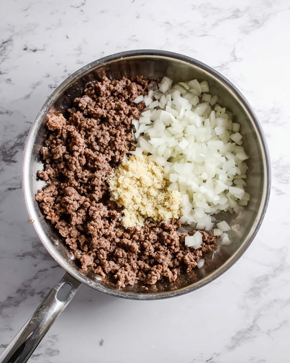 A shiny silver pan on a white marbled surface holds three main layers: on the left and bottom side, a layer of browned ground beef with small, crumbly texture in light and dark brown shades; to the right side, there is a pile of chopped white onions with a soft and slightly translucent look; near the bottom center, there is a smaller mound of finely minced yellowish garlic or ginger paste with a slightly grainy texture. The ingredients are visibly separate and ready for mixing. Photo taken with an iphone --ar 4:5 --v 7