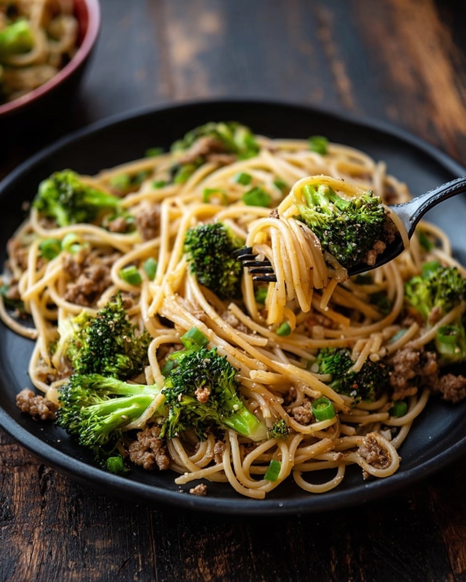A black plate filled with a dish of light brown spaghetti noodles tangled together, mixed with bright green broccoli florets scattered evenly. Small pieces of cooked ground meat are spread throughout the noodles, along with chopped green onions adding a touch of color. A black fork picks up a twisted small bundle of noodles with some broccoli and meat. The background is a dark rustic wood texture. Photo taken with an iphone --ar 4:5 --v 7