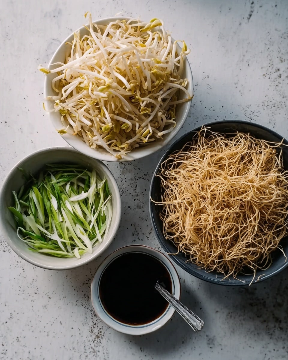The image shows four bowls on a white marbled surface. Starting from the top, the first bowl contains a pile of pale yellow bean sprouts with some brownish tips. Below it, there is a bowl filled with long, thin, shredded light tan dry noodles, filling the bowl. To the left, there is a smaller bowl holding thin green strips mixed with white strips, likely sliced spring onions. At the bottom, a bowl holds a dark liquid sauce with a spoon inside it. photo taken with an iphone --ar 4:5 --v 7