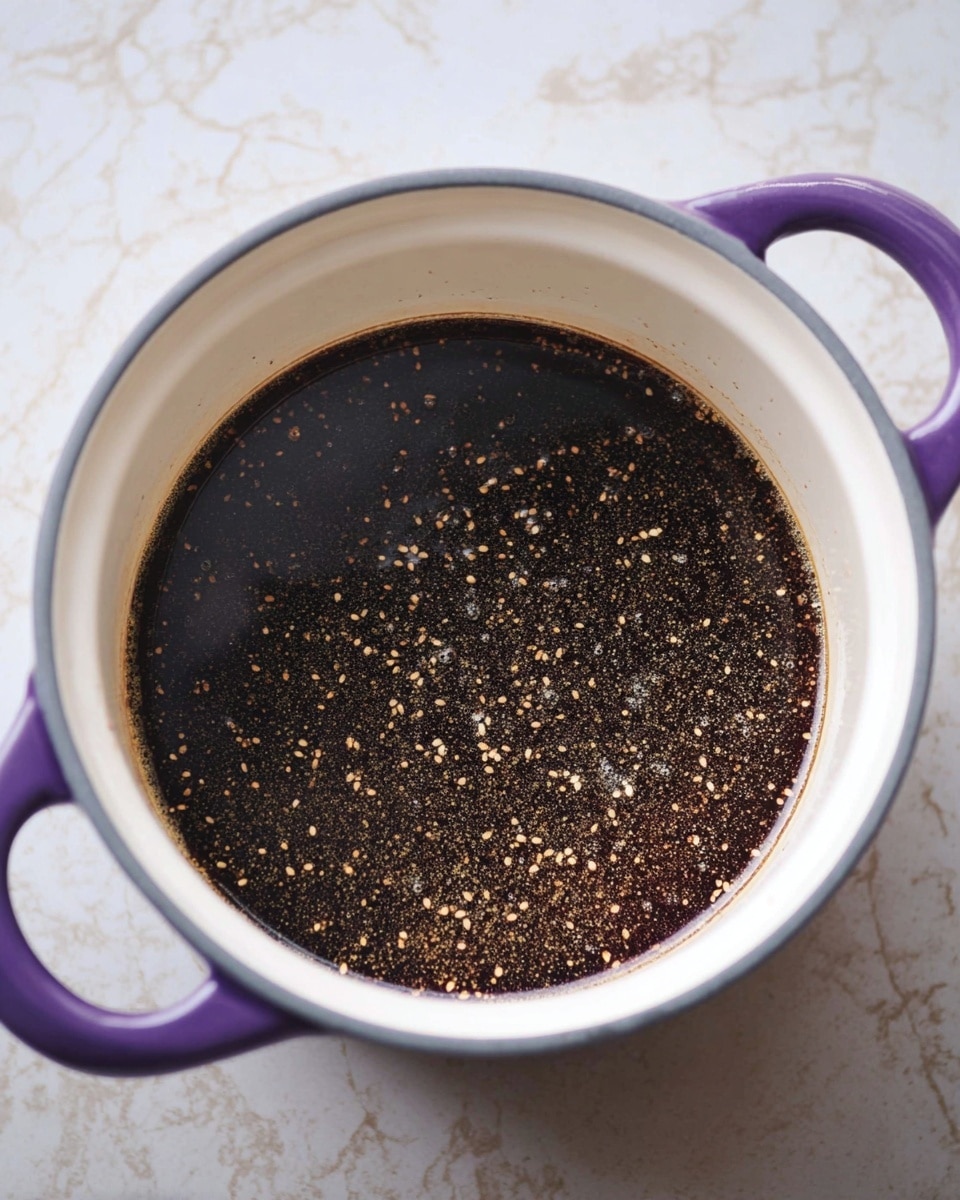 A white enamel pot with purple handles sits on a surface with a white marbled texture, filled with a dark brown liquid that has many tiny beige and light brown specks floating throughout, showing a somewhat thick texture with bits evenly dispersed in the liquid, creating a shiny and slightly oily surface. photo taken with an iphone --ar 4:5 --v 7