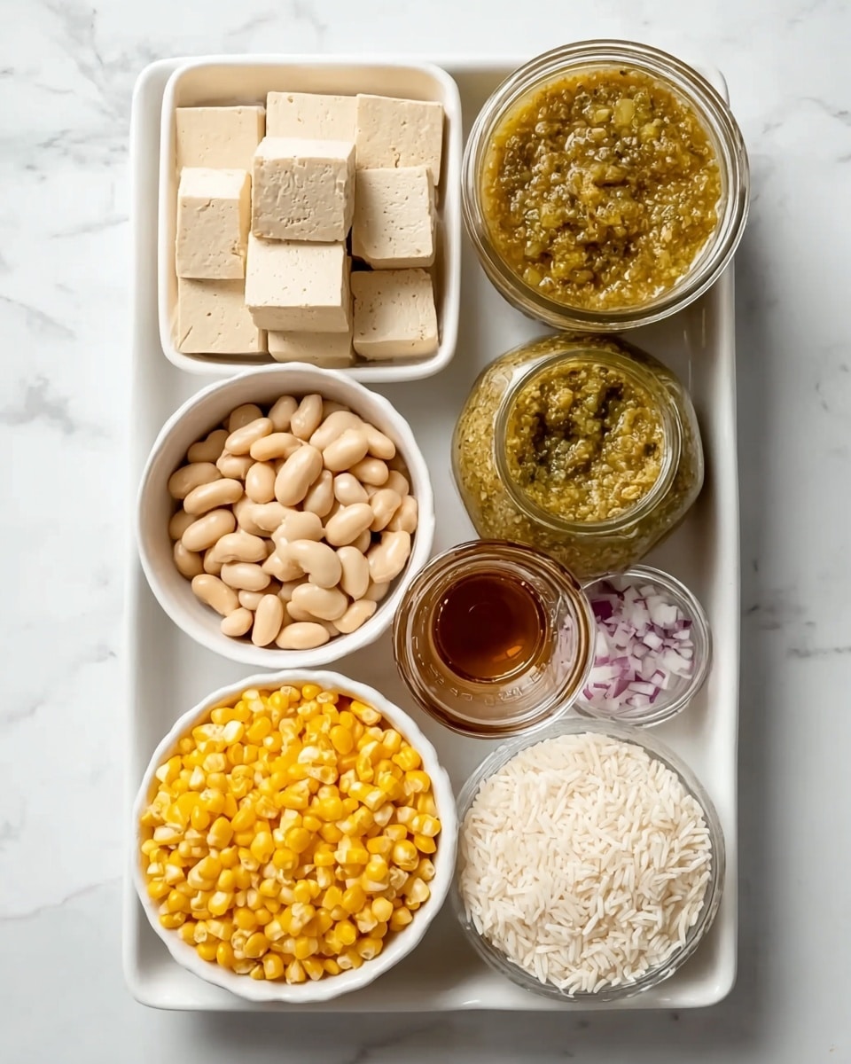A rectangular white dish contains neatly arranged ingredients separated into sections. In the top left corner, there are four light beige tofu cubes with smooth texture. Next to the tofu on the right side is a small round container filled with chunky green salsa. Below the salsa is a small glass bowl holding finely chopped raw red onions with visible texture. In the center left of the dish, a small white bowl is filled with pale beige white beans, the smooth beans closely packed together. Below the beans, a small pile of bright yellow corn kernels spreads across the bottom left corner. To the right of the corn, a smaller glass bowl is filled with chunky green chili sauce. On the bottom right corner, a small white bowl contains uncooked white rice grains that look dry and separate. In the center right, there is a small glass container with a dark amber liquid. The background surface is white marble. Photo taken with an iphone --ar 4:5 --v 7