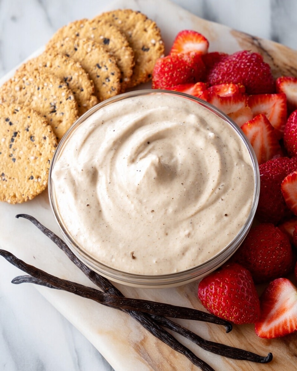 The image shows a round clear glass bowl filled with a creamy, light beige dip that has a smooth texture with slight swirls on the surface. Around the bowl on the white marbled surface, there are fresh sliced strawberries with red and white colors mostly placed at the bottom, and some light brown, round, thin crackers with visible dark seeds are arranged at the top of the bowl. Two long vanilla pods lay diagonally across the surface near the crackers, adding a dark brown color contrast to the scene. Photo taken with an iphone --ar 4:5 --v 7