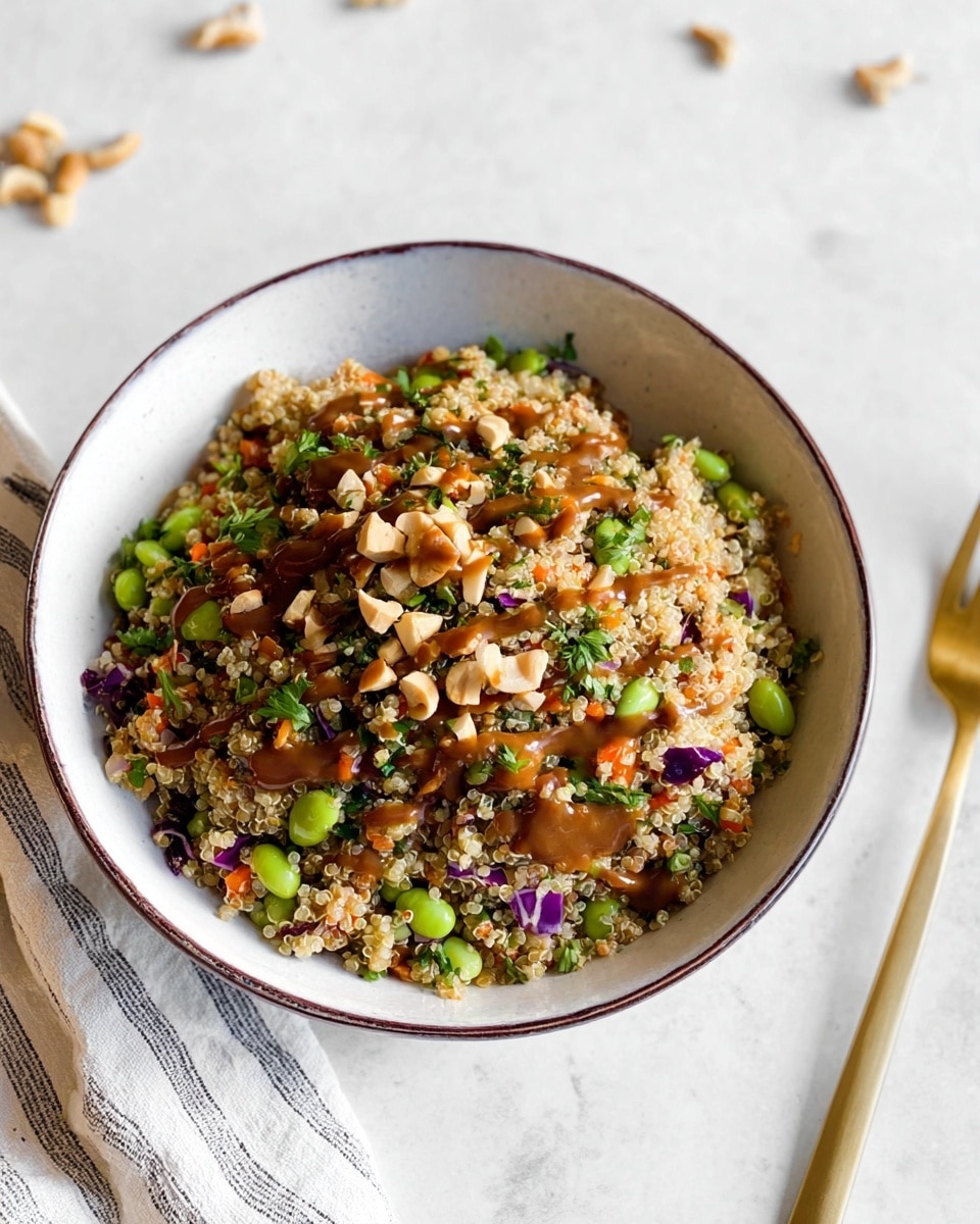 A white bowl with a thin dark rim holds a mixed grain salad made of small beige quinoa grains forming the main layer. Inside the quinoa, there are scattered pieces of green edamame beans, small orange carrot bits, and some purple cabbage pieces, adding color and texture. On top, there is a drizzle of thick brown sauce and chopped light brown nuts, with fresh green herbs sprinkled all over. The bowl sits on a white marbled surface with some scattered nuts around, and a gold fork lies partially in the scene near a striped cloth. photo taken with an iphone --ar 4:5 --v 7