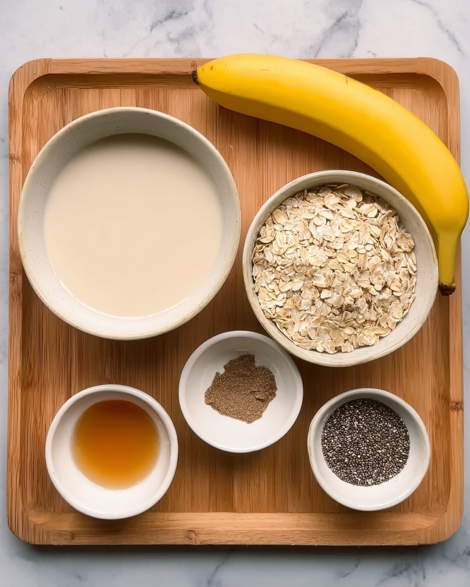 A wooden tray holds six white bowls and a yellow banana. The largest bowl on the left is filled with a light beige creamy liquid. To the right, a medium white bowl is full of dry oats, showing their light tan color and rough texture. Above the oats, a small white bowl contains a dark brown powder. Next to it, another small white bowl has a clear amber liquid. Below, a small white bowl holds black chia seeds with a rough appearance. The ripe yellow banana is placed on the right side of the tray. The tray is set on a white marbled surface. Photo taken with an iphone --ar 4:5 --v 7