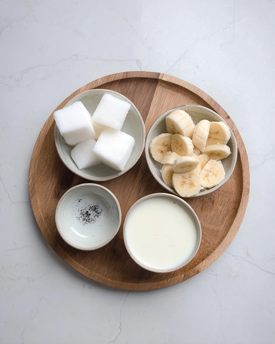 A round wooden board holds four small white bowls arranged in a loose square: the top left bowl contains five large white ice cubes with smooth surfaces, the top right bowl is filled with many light yellow banana slices showing their inner soft texture, the bottom left bowl is empty except for small black specks at the center, and the bottom right bowl holds creamy white liquid with a smooth top. The whole setup sits on a white marbled surface. Photo taken with an iphone --ar 4:5 --v 7