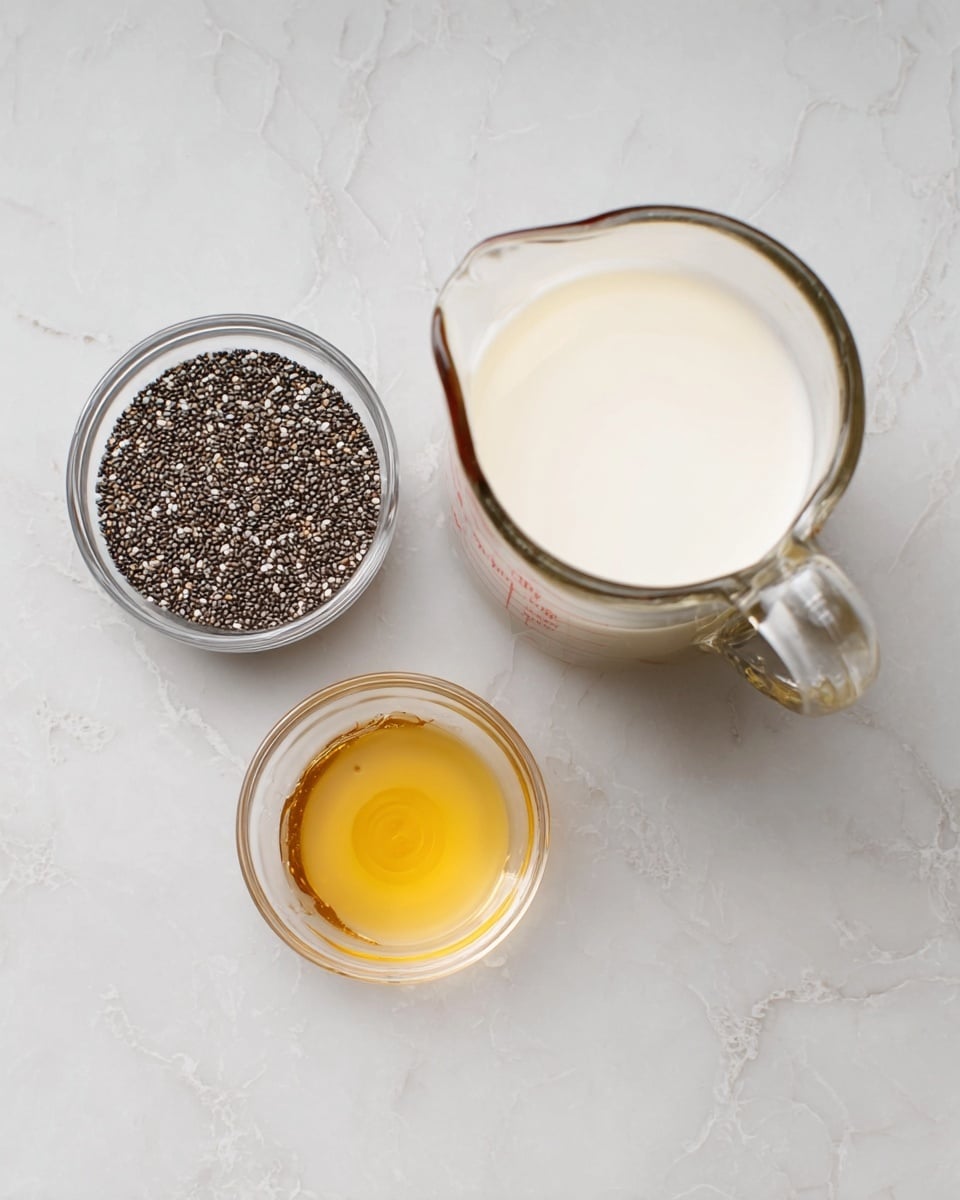 The image shows three clear glass containers placed on a white marbled surface. The largest container on the right is a measuring jug filled halfway with white liquid. Above it, there is a medium-sized bowl filled with small black and white chia seeds. Below the chia seeds, there is a small bowl holding a light golden liquid, likely honey or syrup. The simple arrangement highlights the different textures and colors of the ingredients clearly. photo taken with an iphone --ar 4:5 --v 7