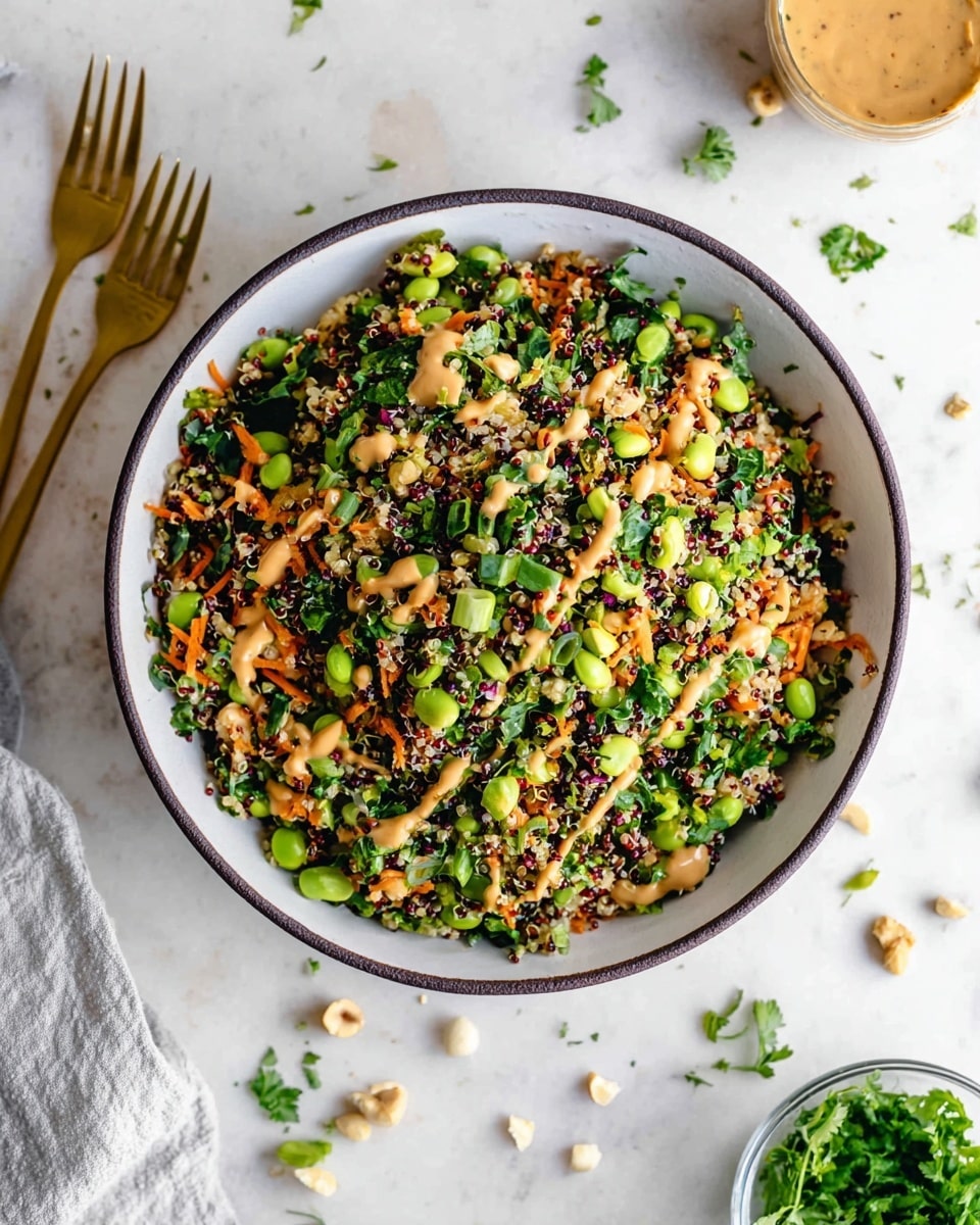 A bowl filled with a colorful salad showing many small pieces in layers, including green peas or edamame, shredded orange carrots, chopped green onions, and finely chopped leafy greens mixed with quinoa grains creating a textured look. There is a creamy light brown sauce drizzled over the top and some sprinkled seeds adding a little white and crunch. The bowl is white with a dark rim, placed on a white marbled surface with scattered green herbs and crushed nuts around. A woman's hand is not visible, but a gold fork is on the left side and a small container with fresh green herbs is at the bottom right. photo taken with an iphone --ar 4:5 --v 7