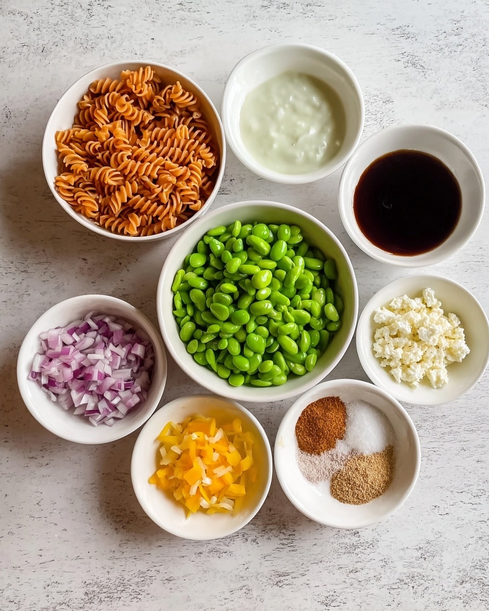 The image shows nine small white bowls placed on a white marbled surface. The top left bowl contains orange-brown spiral pasta. To its right, there is a bowl with dark brown liquid and another bowl with a white creamy sauce. Below these, there is a larger bowl filled with bright green shelled edamame. Below the pasta and sauces, there are five smaller bowls arranged in a circle, containing diced red onions, yellow chopped bell peppers, crumbled white cheese, granulated brown powder, and fine white powder. The colors are bright and the ingredients are clearly visible. photo taken with an iphone --ar 4:5 --v 7