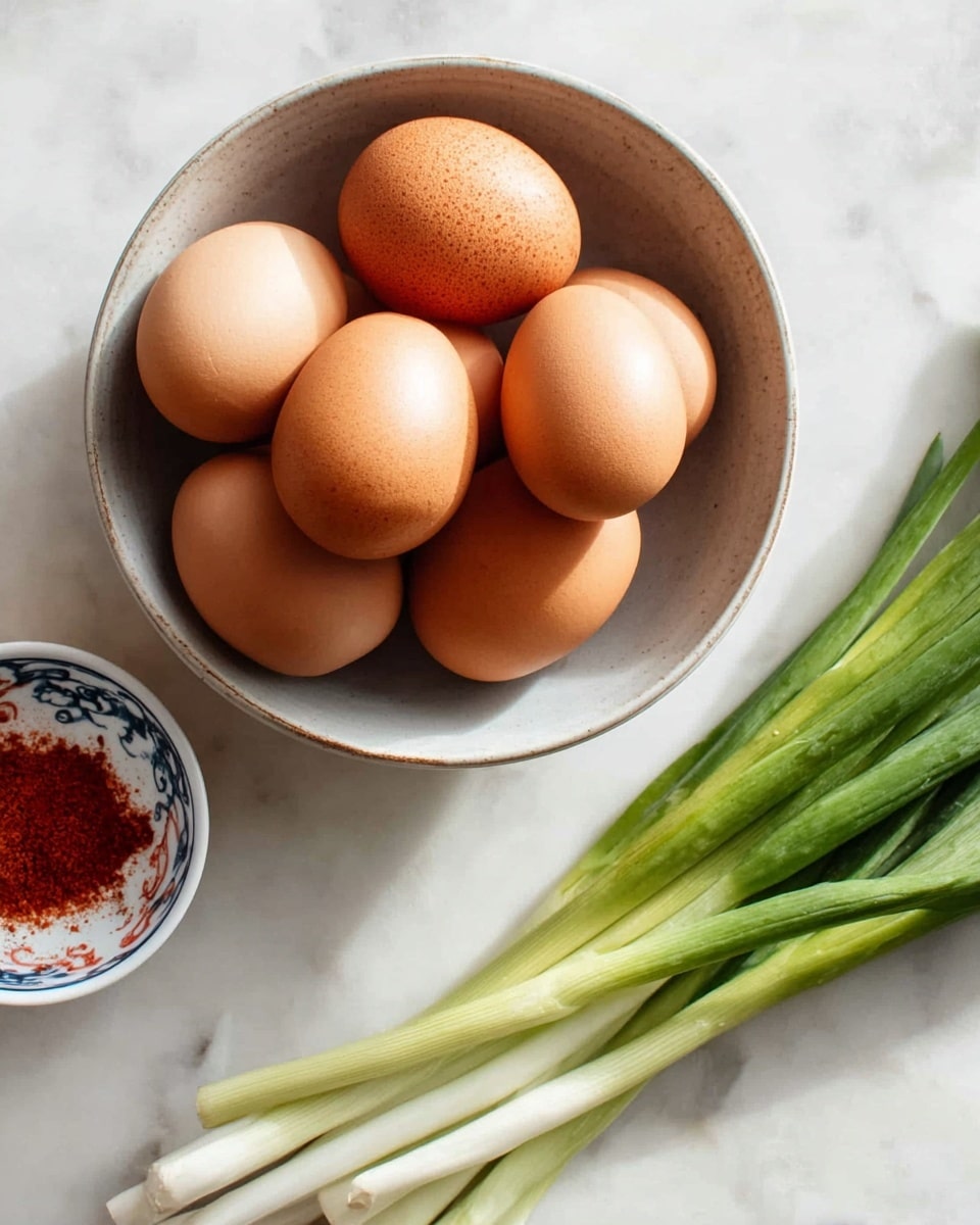 A ceramic bowl with a light gray inner surface holds five smooth brown eggs, arranged close together. To the right side, six fresh green onions with white bulbs lie next to the bowl on a white marbled surface. A small white bowl with a blue and red pattern on its edge contains red powder and is placed near the green onions on the same white marbled texture. The scene is softly lit, focusing on the natural colors and textures of the ingredients. photo taken with an iphone --ar 4:5 --v 7