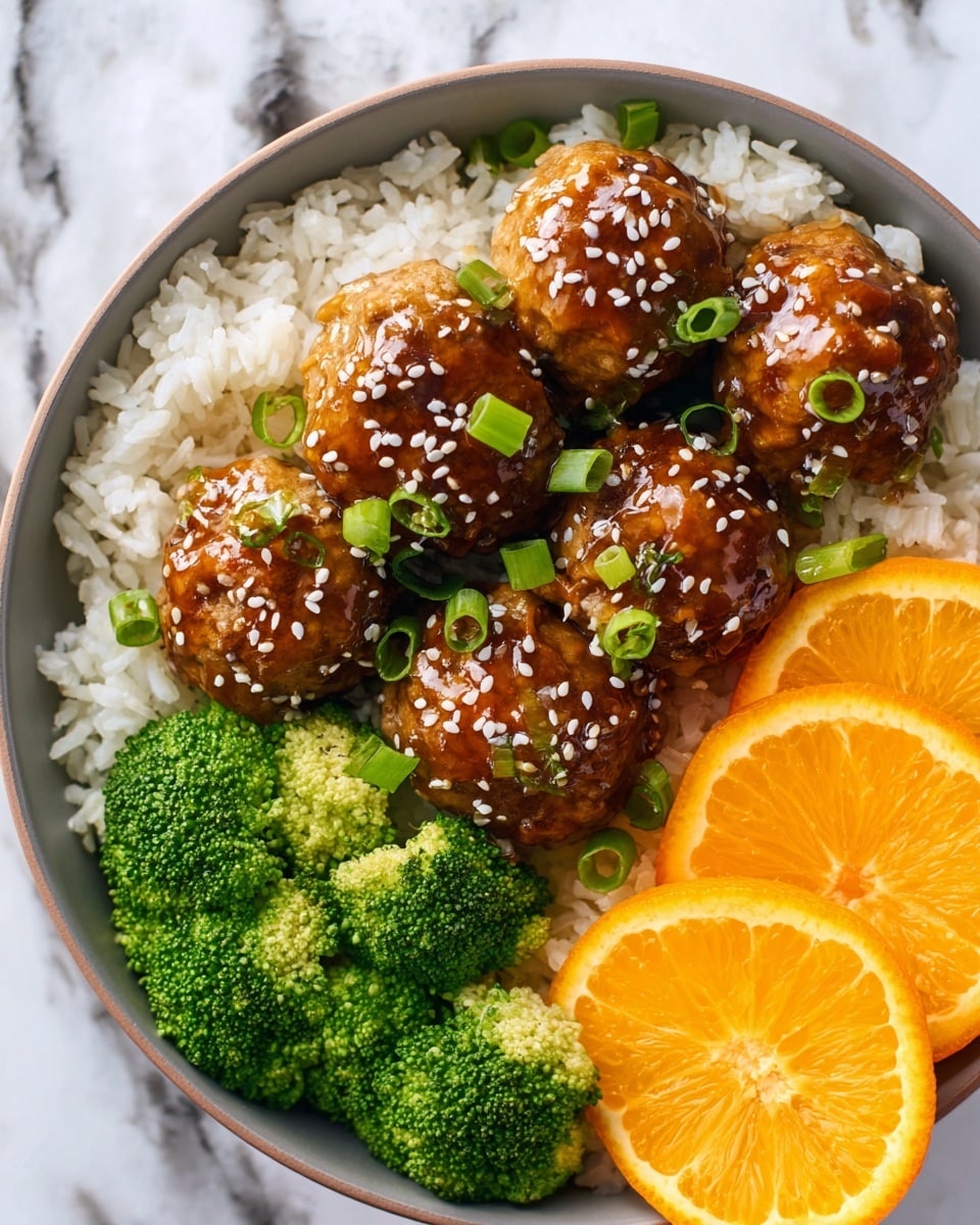 A white bowl filled with a bed of white cooked rice forms the base layer, topped with six round brown meatballs covered in a shiny brown sauce sprinkled with white sesame seeds and small green slices of scallion on top. To one side of the bowl, bright green steamed broccoli florets add a fresh pop of color, and on the opposite side, two thick slices of bright orange citrus fruit rest on the rice. The bowl sits on a white marbled surface. photo taken with an iphone --ar 4:5 --v 7
