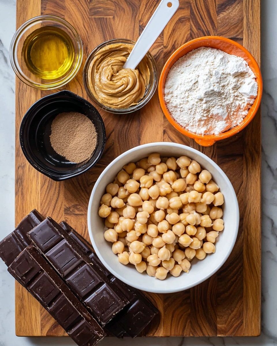 The image shows a white bowl filled with round, beige chickpeas placed on a wooden board with a rich brown pattern. Around the bowl, there are several measuring cups and a small black bowl: a white measuring cup with light brown peanut butter, a white measuring spoon holding white baking soda, an orange measuring cup filled with white flour, a small black bowl of light brown sugar, and a white bowl with golden liquid, likely oil. At the bottom left, there are five rectangular blocks of dark chocolate stacked slightly unevenly. The background is a white marbled texture. Photo taken with an iphone --ar 4:5 --v 7