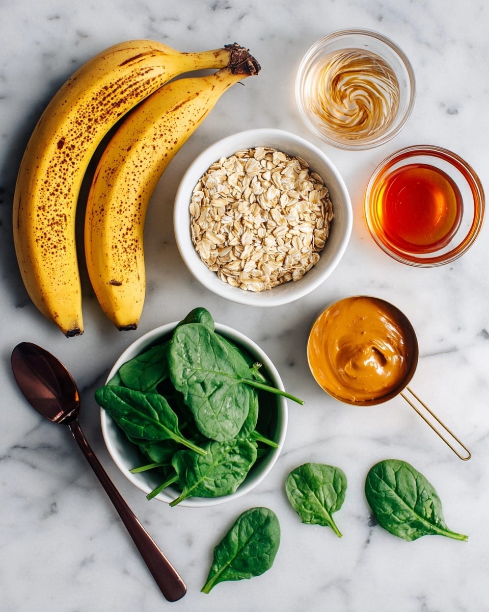 The image shows ingredients on a white marbled surface. There are two ripe bananas with brown spots on their yellow peel, placed on the left. Below them is a white bowl filled with fresh green spinach leaves. To the right of the spinach is a golden measuring cup with light tan oats. Above the oats is a small clear bowl filled with amber-colored syrup. Above that is a clear glass container with a mixture of light beige liquid and darker brown swirls inside. Below the spinach and oats is another golden measuring cup with orange peanut butter. Two spinach leaves lie directly on the white marbled surface near the bottom. The utensils holding the oats and peanut butter have dark wooden handles. Photo taken with an iphone --ar 4:5 --v 7